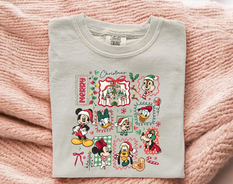 May include: A light gray Comfort Colors sweatshirt featuring a colorful Christmas-themed graphic. The graphic includes various Disney characters like Mickey, Minnie, Donald, and Chip and Dale, along with the text "Merry Christmas".