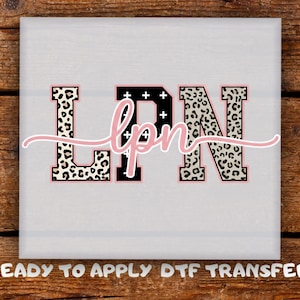 May include: A white square with the letters "LPN" in a bold, blocky font. The "L" and "N" have a black and white leopard print pattern, while the "P" is black with white crosses. The letters "lpn" are in a cursive pink font. The text "READY TO APPLY DTF TRANSFER" is at the bottom.