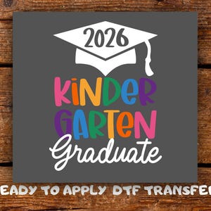 May include: A dark grey square DTF transfer featuring a white graduation cap with the year 2026 printed on it. Below the cap, the word KINDERGARTEN is written in colourful, bold letters, followed by the word Graduate in white script lettering.