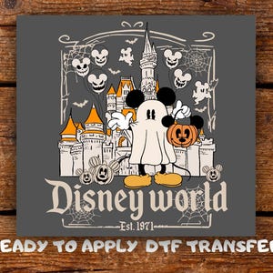 May include: A gray graphic transfer featuring a ghost-costumed Mickey Mouse holding an orange pumpkin bucket in front of a castle. The design includes Mickey-shaped balloons, spiderwebs, bats, and the text Disney world Est. 1971.