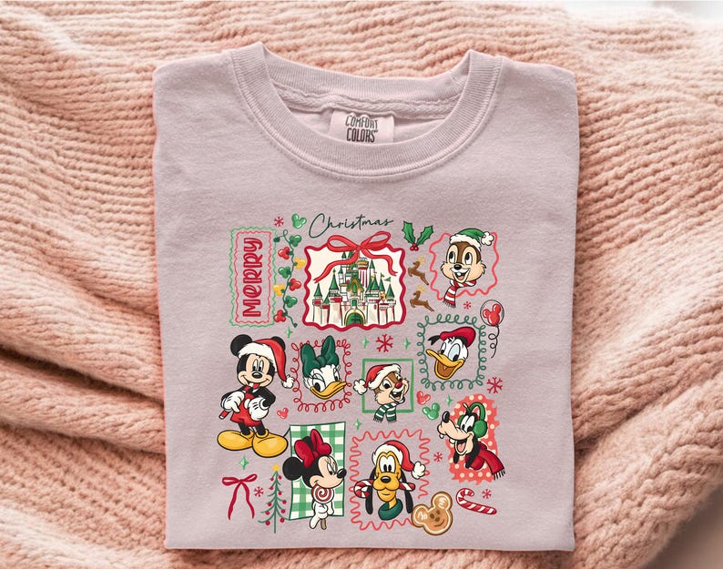 May include: A light purple Comfort Colors sweatshirt featuring a festive Christmas design. The design includes various Disney characters like Mickey, Minnie, Donald, and Goofy, all wearing Santa hats. The words "Merry Christmas" are also included in the design.