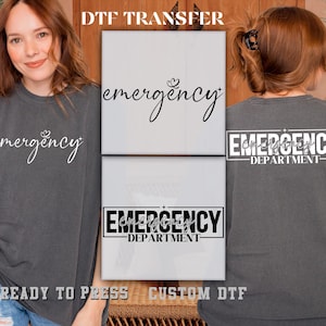 May include: Dark grey t-shirts with the word "emergency" in white script. One shirt has the text on the front, and the other has "emergency department" on the back. The image also shows a DTF transfer.