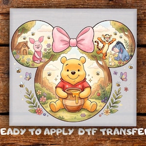 May include: A DTF transfer featuring Winnie the Pooh and friends. The design includes Winnie the Pooh holding a honey pot, Piglet, Tigger, Eeyore, and other characters. A large pink bow is at the top of the design. The text "READY TO APPLY DTF TRANSFER" is at the bottom.