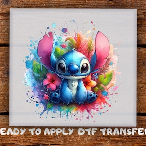 May include: A vibrant image of a blue cartoon character with large eyes and ears, set against a backdrop of colourful watercolour splashes, flowers, and leaves. The text "READY TO APPLY DTF TRANSFER" is at the bottom.