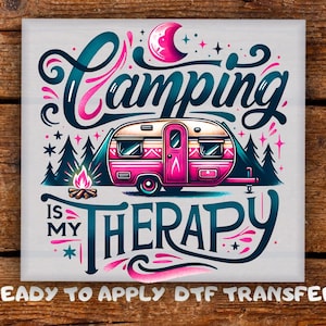May include: A square graphic with the words "Camping is My Therapy" in teal and pink script. A pink camper is centered, with a campfire and trees on either side. The words "Ready to Apply DTF Transfer" are at the bottom.