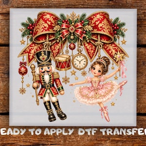 May include: A ready to apply DTF transfer featuring a nutcracker in a red and green uniform holding a staff, a ballerina in a pink tutu holding a star wand, a large red bow, a drum, a pocket watch, and ornaments on a light gray background.