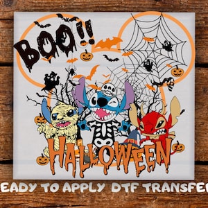 May include: A Halloween-themed graphic featuring three cartoon characters dressed in costumes. The word "Boo!!" is above the characters, and the word "Halloween" is below. Bats, pumpkins, and a spiderweb complete the design.