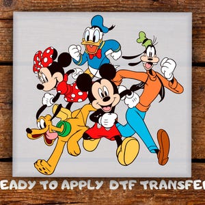 May include: A DTF transfer featuring Mickey Mouse, Minnie Mouse, Donald Duck, Goofy, and Pluto. Mickey Mouse is wearing red shorts, and Minnie Mouse is wearing a red dress with white polka dots. The text "READY TO APPLY DTF TRANSFER" is at the bottom.
