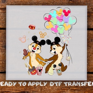 May include: A DTF transfer featuring Chip and Dale holding hands, surrounded by colorful Mickey Mouse-shaped balloons, popcorn, pretzels, and lollipops. The image includes the text "READY TO APPLY DTF TRANSFER".