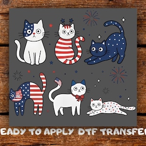May include: A grey square featuring six cartoon cats with patriotic designs, including stars and stripes. The cats are in various poses, with fireworks and stars scattered around them. Text at the bottom reads "READY TO APPLY DTF TRANSFER".