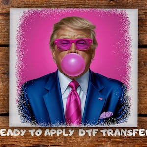 May include: A portrait of a man wearing pink sunglasses and blowing a bubble gum bubble. He is wearing a blue suit with a pink tie and pocket square. The image has a pink background with a white border and the text "READY TO APPLY DTF TRANSFER".