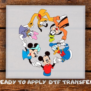 May include: A gray square featuring a colourful illustration of Disney characters, including Mickey Mouse, Minnie Mouse, Donald Duck, Goofy, Pluto, and Daisy Duck, arranged in a circle. The text "READY TO APPLY DTF TRANSFER" is at the bottom.
