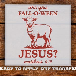 May include: A square white DTF transfer featuring a red illustration of a lamb standing on grass. The text in red reads: are you FALL-O-WEEN JESUS? matthew 4:19. Below the square, the white text reads: READY TO APPLY DTF TRANSFER.