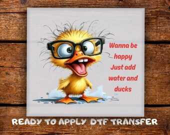 May include: A square image features a cartoon duckling wearing black-framed glasses. The duckling has an open beak and is surrounded by the text "Wanna be happy, Just add water and ducks." The words "READY TO APPLY DTF TRANSFER" are at the bottom.
