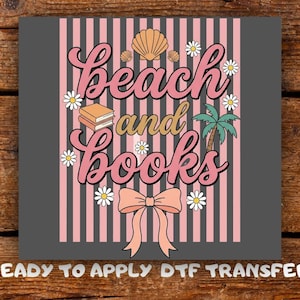 Peut inclure: Un graphisme avec les mots "beach and books" en script rose, avec un coquillage, un palmier, des marguerites et un nœud. Le design est sur un fond gris avec des rayures verticales roses. Le texte "READY TO APPLY DTF TRANSFER" est en bas.