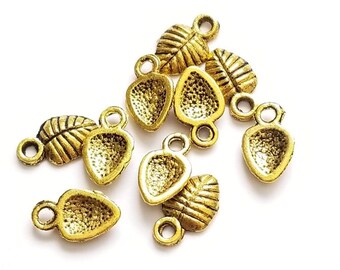 May include: A group of 10 gold-toned metal charms featuring a leaf design and a heart shape. The charms have a loop at the top for attaching to jewelry or other crafts.