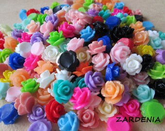 May include: A large assortment of colorful plastic rose flower embellishments. The roses are in various shades of pink, red, blue, green, yellow, orange, and white.