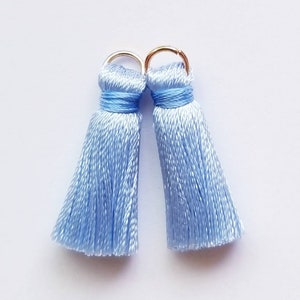 May include: Two light blue silk tassels with gold metal rings at the top.
