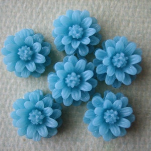 K&ouml;nnte beinhalten: Sechs blaue, blumenf&ouml;rmige Cabochons. Die Cabochons sind aus Harz und haben eine gl&auml;nzende Oberfl&auml;che.