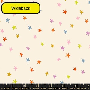 May include: A cream-colored fabric featuring a scattered pattern of hand-drawn style stars in orange, pink, yellow, and blue. A yellow label at the top reads Wideback. A black ruler at the bottom shows 7 inches with the text Ruby Star Society.