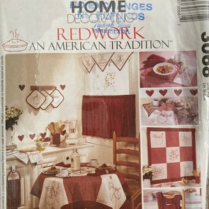 Peut inclure: Un patron de broderie rouge vintage McCall's Home Decor représentant une scène de cuisine avec une table, des chaises et divers articles brodés. Le patron comprend des instructions pour réaliser une nappe, des sets de table, une traverse de fenêtre et une courtepointe. Le patron est intitulé "Redwork: An American Tradition".