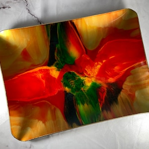 May include: A rectangular tray with a gold rim and a colourful abstract design. The design features swirls of red, orange, yellow, green, and black.