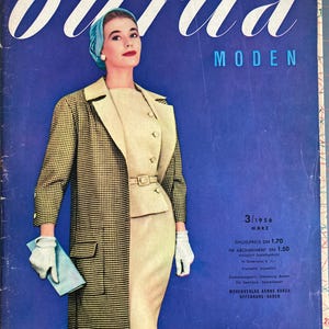 May include: A vintage magazine cover featuring a woman wearing a light blue hat and a black and white checked coat. The magazine is titled "burda MODEN" and the date is 3/1956. The text on the cover also includes the price and subscription information.