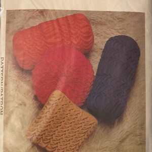 May include: Image of a set of three smocked cushions in different shapes and colours. The cushions are red, navy blue, tan, and orange. The image also includes the text "4647 Set of three Smocked Cushions."