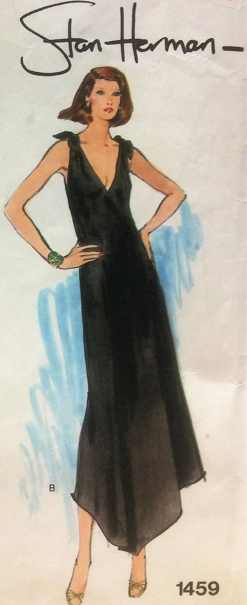 Puede incluir: Un vestido negro sin mangas con escote en V y falda fluida. El vestido se muestra en una modelo con cabello casta&ntilde;o sobre un fondo neutro. El texto "Stan Herman" y "1459" es visible en la imagen.