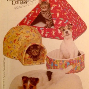 May include: A sewing pattern for a Cozy Critters pet bed. The pattern includes instructions for making a red and white tent-style bed, a yellow and white igloo-style bed, and a round bed with a colourful print. The pattern is from Butterick and has the number 5903.