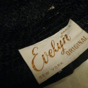 Puede incluir: Etiqueta blanca con letras doradas que dicen "Evelyn Original" con "New York" y "Paris" impresas debajo. La etiqueta est&aacute; unida a una tela negra.