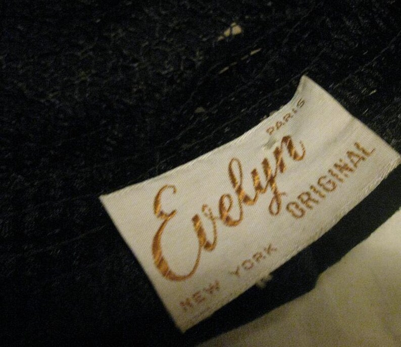 Puede incluir: Etiqueta blanca con letras doradas que dicen "Evelyn Original" con "New York" y "Paris" impresas debajo. La etiqueta est&aacute; unida a una tela negra.