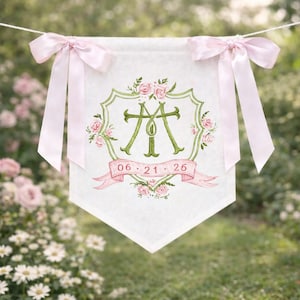 May include: White banner with pink bows, green floral design, and the letters "M" and "T". The banner has a pink ribbon with the date "06.21.26" and is hanging on a string.