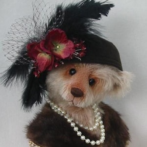 Könnte beinhalten: Ein Teddybär, der einen schwarzen Hut mit einer roten und weißen Blume und einer Perlenkette trägt. Der Hut hat eine schwarze Feder und einen schwarzen Netzschleier.