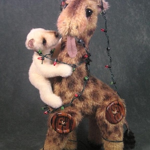 May include: A brown and tan stuffed giraffe with a long neck and a white stuffed animal riding on its back. The giraffe is decorated with a string of Christmas lights.