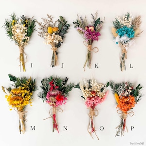 Puede incluir: Una colecci&oacute;n de ocho peque&ntilde;os ramos de flores secas, cada uno atado con hilo. Los ramos presentan una variedad de colores, incluyendo amarillo, blanco, rosa, rojo y azul. Cada ramo est&aacute; etiquetado con una letra de la I a la P.