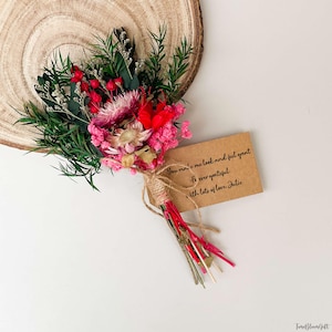 Puede incluir: Un peque&ntilde;o ramo de flores secas con elementos rojos, rosas y verdes, atado con hilo. Se adjunta una peque&ntilde;a tarjeta marr&oacute;n con texto escrito a mano. El texto dice: "You make me look and feel great. For ever grateful. With lots of love, Julie."
