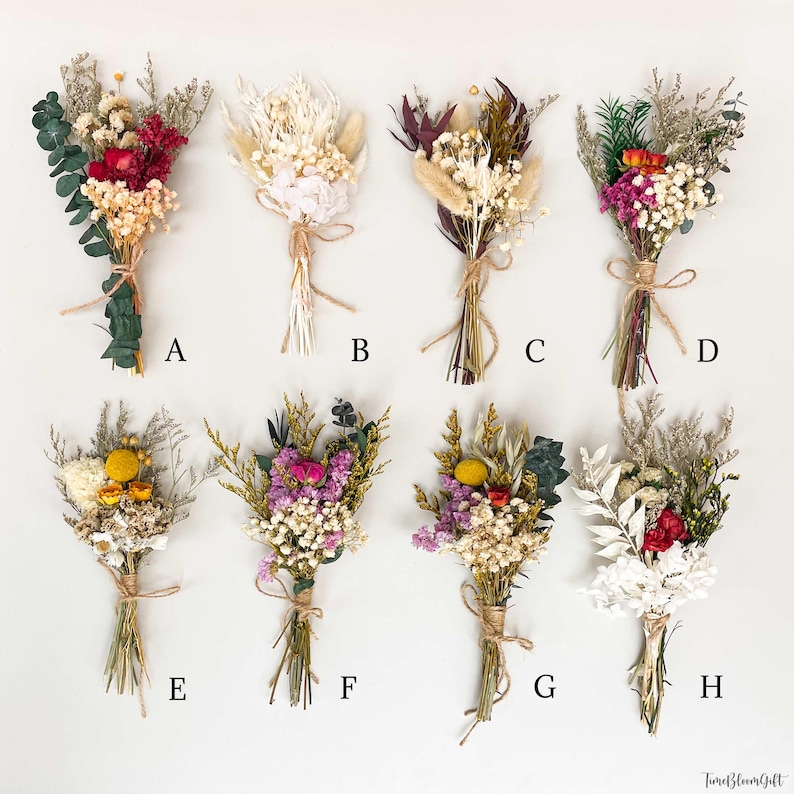 Puede incluir: Ocho peque&ntilde;os ramos de flores secas, cada uno atado con hilo. Los ramos presentan una variedad de colores, incluyendo rojo, blanco, morado y amarillo. Los ramos est&aacute;n dispuestos sobre una superficie blanca. La imagen incluye el texto "TureBloomGift".