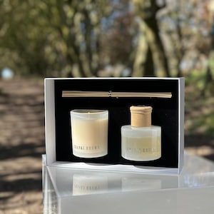 Könnte beinhalten: Ein Geschenkset mit einer Kerze und einem Diffusor mit Stäbchen, präsentiert in einer weißen Box. Kerze und Diffusor befinden sich in transparenten Glasbehältern mit dem Text "FRANKI BROWN". Die Kerze ist angezündet.