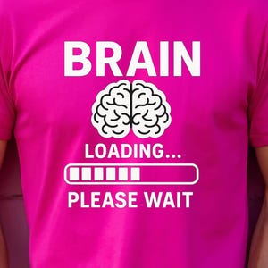 May include: A magenta t-shirt with the words "BRAIN" and "LOADING... PLEASE WAIT" in white, along with a brain graphic. The shirt is short-sleeved and worn by a person.