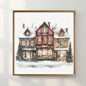 May include: A cross-stitch pattern depicting a row of three multi-story buildings covered in snow. The central building is red, flanked by two grey structures. All buildings feature lit windows, festive garlands, and evergreen trees on the sides.