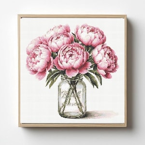 May include: A framed cross-stitch of pink peonies in a glass jar. The flowers are a vibrant pink with green leaves, and the jar has a vintage aesthetic. The artwork is set against a white background.