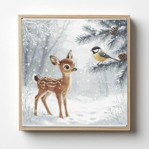 May include: A framed cross-stitch artwork depicts a winter scene with a young deer and a bird. The deer is brown with white spots, standing in the snow. A yellow and black bird perches on a snow-covered pine branch. The artwork is in a light wood frame.