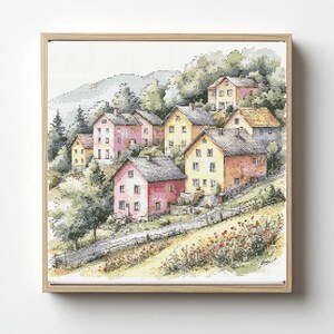 Peut inclure: Une broderie encadrée représentant un village à flanc de colline. Les maisons, aux tons roses, jaunes et orangés, sont nichées parmi des arbres verts. Un chemin de terre et des fleurs sauvages mènent au village, avec une montagne en arrière-plan.