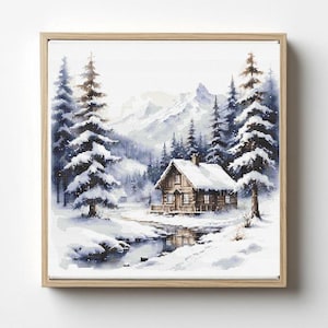 Op de afbeelding: Een ingelijste kruissteek die een winterlandschap uitbeeldt. Een met sneeuw bedekte hut staat in de buurt van een beek, omringd door met sneeuw bedekte dennenbomen en bergen. Het kunstwerk is ingelijst in een lichtgekleurde houten lijst.