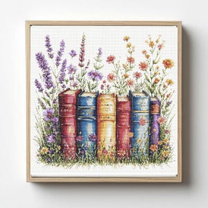 Może przedstawiać: Haft krzyżykowy przedstawiający rząd kolorowych książek z kwiatowymi akcentami. Książki są w odcieniach czerwieni, niebieskiego i żółtego, z precyzyjnymi przeszyciami. Lawenda, pomarańczowe i fioletowe kwiaty otaczają książki na białym tle.