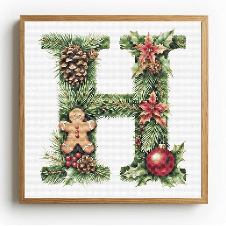 May include: Cross-stitch artwork of the letter "H" decorated with Christmas elements. The letter is formed from green pine needles and adorned with a pinecone, gingerbread man, red berries, poinsettias, and a red ornament. The artwork is framed in a wooden frame.