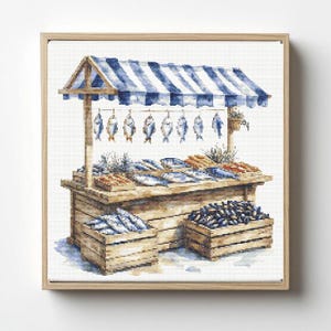 Puede incluir: Pintura a la acuarela de un puesto de mercado de pescado con un toldo a rayas azules y blancas. Cajas de madera exhiben varios tipos de pescado, algunos colgados del toldo. La obra de arte está enmarcada en un marco de madera clara.