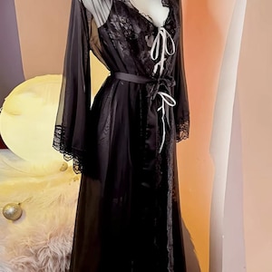 May include: A black sheer robe with lace trim and a matching lace slip. The robe has a satin sash and a V-neckline.
