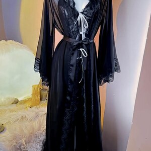 May include: A black sheer robe with lace trim and a satin sash. The robe has long sleeves and a V-neckline.